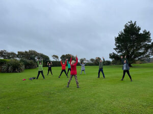 Yoga retreat guests at Lanhydrock Hotel practising outside on the golf course